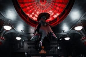 A striking sculpture of a witch on a broomstick suspended under a glowing red dome at Blackcraft in Salem, Massachusetts, with dramatic gothic architecture adding to the eerie atmosphere.