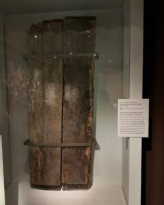 Two large, weathered wooden wall planks on display from an old jail in salem massachusetts, showing their rough texture and worn surface.