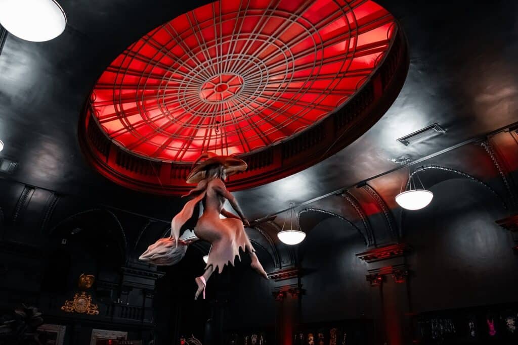 A dramatic red-domed ceiling featuring a witch sculpture on a broomstick in the mystical interior of Blackcraft, located in Salem, Massachusetts.