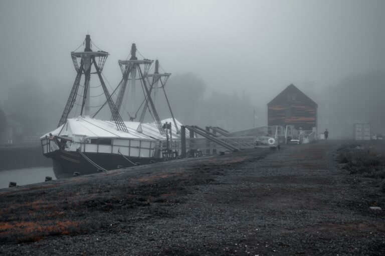 The Friendship of Salem ship docked on a foggy morning at Derby Wharf in Salem, Massachusetts, with a misty backdrop and quiet surroundings.