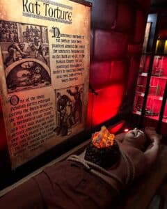 A chilling exhibit at the Museum of Torture in Salem, Massachusetts, showcasing the historical method of rat torture with vivid visuals and a lifelike mannequin.