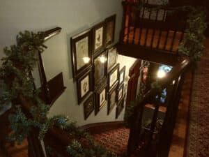 A historic staircase with wooden railings, festive garlands, and framed artwork on the walls, creating a cozy and timeless ambiance in Salem, Massachusetts.