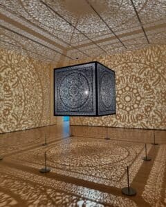 An intricate metal cube art installation at the Peabody Essex Museum in Salem Massachusetts casts beautiful patterns of light and shadow across the walls, ceiling, and floor of the gallery.