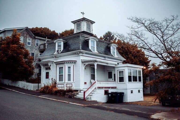 A charming white house with a unique cupola and autumn surroundings in Salem, Massachusetts, famously known as Max and Dani's house from the movie Hocus Pocus.