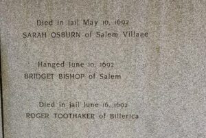 An engraved stone at a Salem memorial commemorating Sarah Osburn, Bridget Bishop, and Roger Toothaker, victims of the Salem witch trials in 1692.
