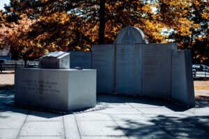 The Salem Village Witchcraft Memorial surrounded by vibrant fall foliage, featuring "The Book of Life" sculpture and engraved panels honoring the victims of the 1692 hysteria.
