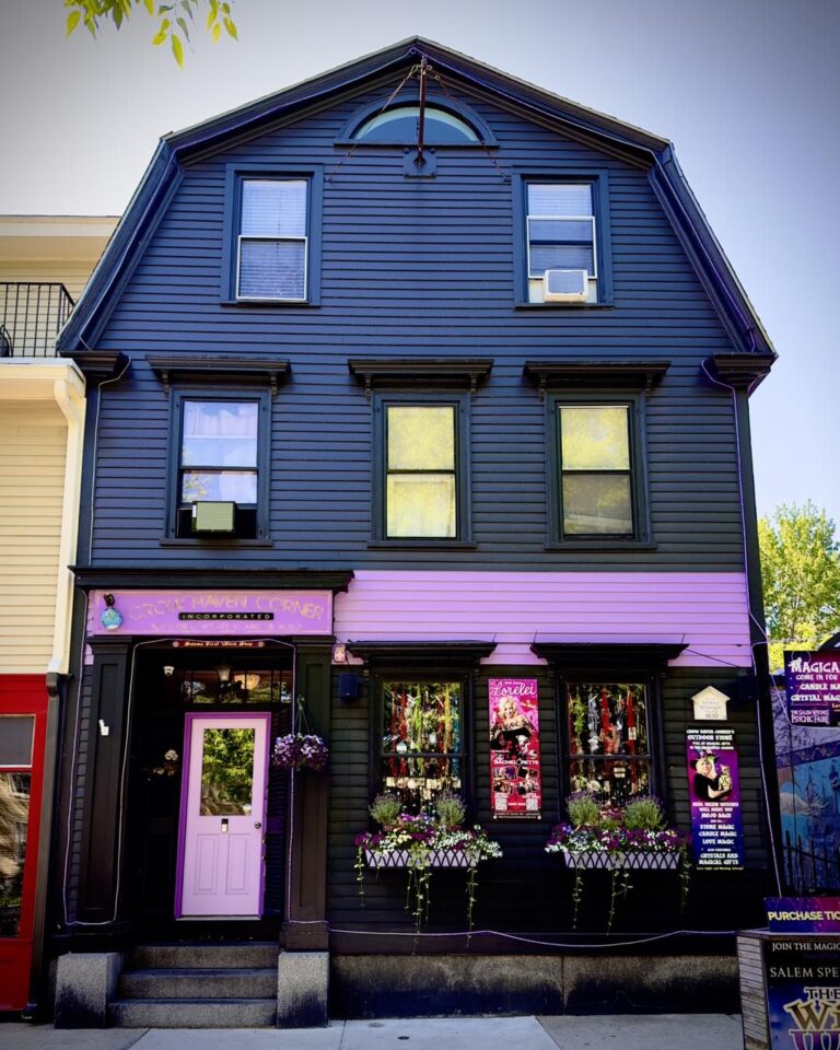 Crow Haven Corner in Salem, Massachusetts, featuring a striking black and purple facade adorned with flower boxes and witch-themed decorations.