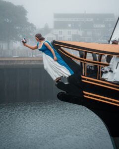 The Friendship of Salem's figurehead, a woman in a blue and white dress holding a bouquet of flowers, seen on a foggy morning in Salem, Massachusetts.