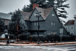 A moody view of the Salem Witch House in Salem, Massachusetts, with dark wooden architecture framed by trees and a cloudy sky, evoking its deep historical significance.